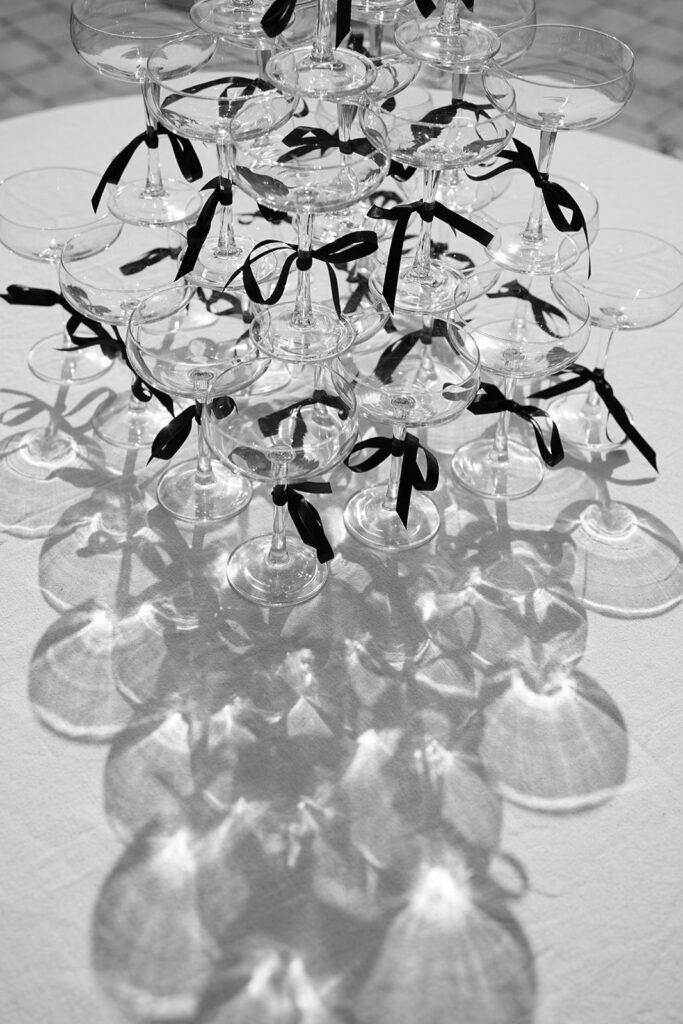 Coupe glasses stacked in tiers cast long shadows across a white table